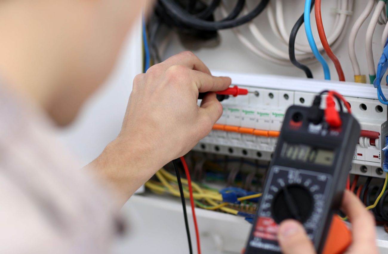 young-electrician-measuring-voltage-fuse-board